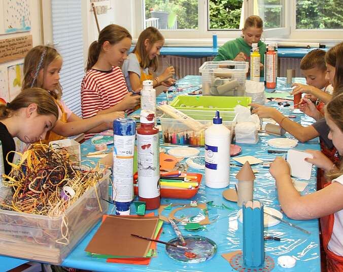 Kinder sitzen am Tisch und malen